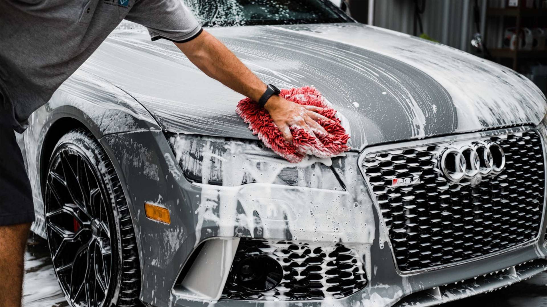 Hand washing foam-covered Audi at detail prep