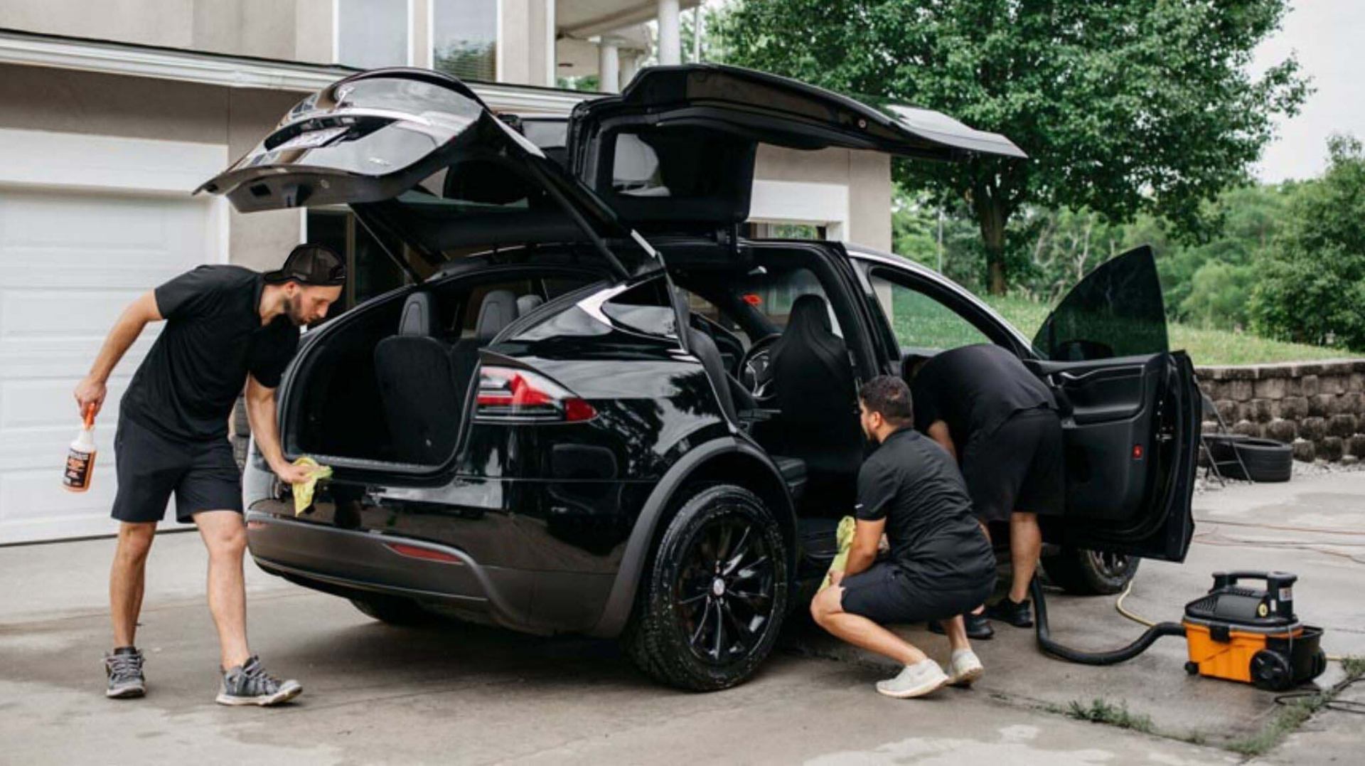 Mobile Hutchins detailers working on black Tesla in a residential driveway